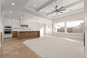 Kitchen featuring ceiling fan, a spacious island, hanging light fixtures, stainless steel appliances, and white cabinets