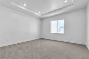 Empty room featuring recessed lighting, a raised ceiling, visible vents, baseboards, and carpet flooring