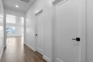 Corridor featuring dark wood-type flooring, visible vents, baseboards, and recessed lighting