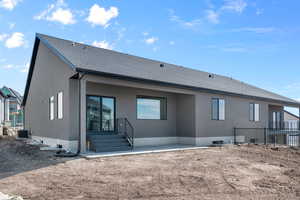 Back of house featuring stucco siding, a shingled roof, central AC unit, and fence