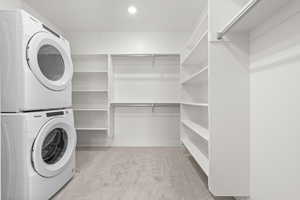 Laundry room with light colored carpet and stacked washer and clothes dryer