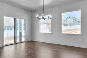 Unfurnished dining area featuring plenty of natural light, baseboards, visible vents, and an inviting chandelier