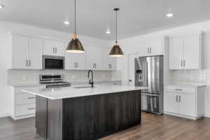 Kitchen featuring dark wood finished floors, tasteful backsplash, appliances with stainless steel finishes, and a sink