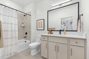 Full bathroom featuring toilet, vanity, shower / bathtub combination with curtain, and tile patterned flooring