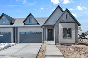View of front of house featuring an attached garage, driveway, and roof with shingles