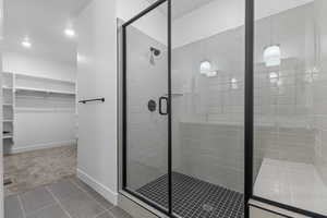 Full bath with tile patterned flooring, a spacious closet, recessed lighting, and a stall shower