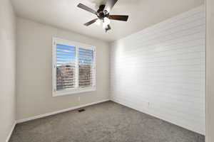 Empty room featuring ceiling fan and carpet flooring