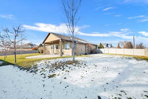 Snow covered back of property with a patio area