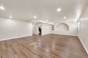 Unfurnished living room with a textured ceiling, dark hardwood / wood-style floors, and built in features