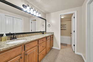 Bathroom with a tub to relax in, vanity, and a textured ceiling