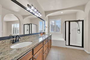 Bathroom featuring tile patterned floors, vanity, and separate shower and tub