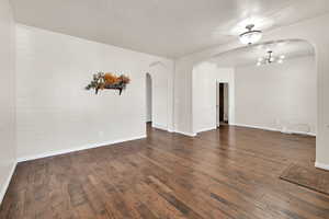 Spare room with dark wood-type flooring and a chandelier