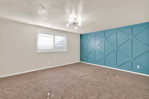 Unfurnished room with a textured ceiling and an inviting chandelier