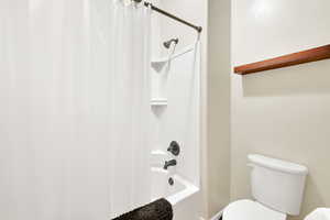 Bathroom with toilet and shower / bath combo with shower curtain