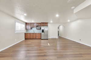 Kitchen featuring appliances with stainless steel finishes, backsplash, light wood-type flooring, a textured ceiling, and sink