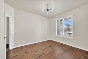 Empty room featuring dark hardwood / wood-style floors and a chandelier