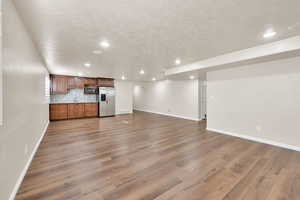 Unfurnished living room with light wood-type flooring, a textured ceiling, and sink