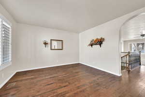 Unfurnished room featuring dark wood-type flooring and ceiling fan