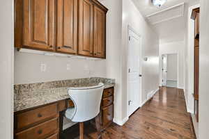 Home office featuring dark hardwood / wood-style flooring and built in desk