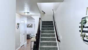 Stairs featuring a textured ceiling and hardwood / wood-style flooring