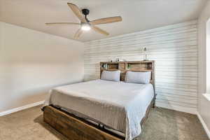 Bedroom featuring wooden walls, carpet floors, and ceiling fan