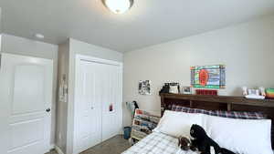 Carpeted bedroom featuring a textured ceiling and a closet