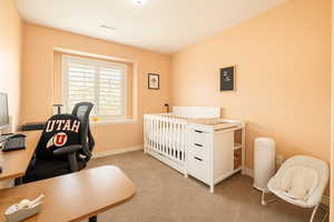 Bedroom featuring carpet, an office area, and baseboards