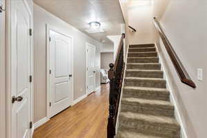 Staircase with wood finished floors and a textured ceiling