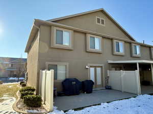 Snow covered rear of property featuring a patio