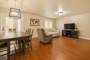 Living room with wood finished floors, a chandelier, and baseboards
