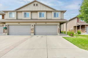 Townhome / multi-family property with board and batten siding, a garage, concrete driveway, and a front yard