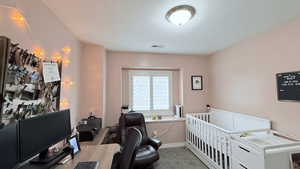 Bedroom featuring light carpet and a nursery area