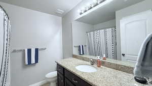 Bathroom featuring toilet, vanity, a shower with curtain, and a textured ceiling