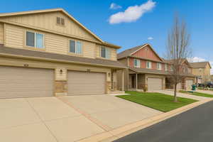View of front of property featuring board and batten siding, stone siding, concrete driveway, and a garage