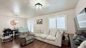 Living room featuring a textured ceiling, dark hardwood / wood-style flooring, and a notable chandelier