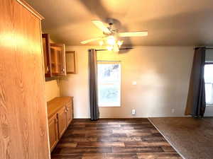 Unfurnished dining area featuring dark wood-type flooring, crown molding, and ceiling fan