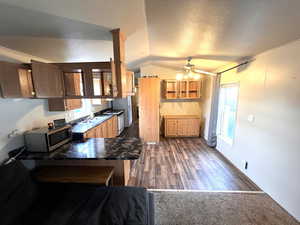 Kitchen featuring white range with gas stovetop, kitchen peninsula, ceiling fan, lofted ceiling, and a textured ceiling