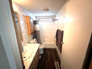 Full bathroom featuring toilet, vanity, shower / bath combination with curtain, and hardwood / wood-style floors