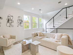 Living area with recessed lighting, stairway, light wood finished floors, and baseboards