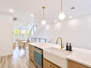 Kitchen featuring a sink, open floor plan, visible vents, light wood-style flooring, and dishwashing machine