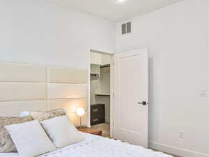 Bedroom with baseboards, visible vents, a closet, and a walk in closet