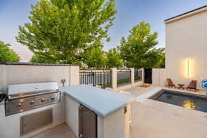 Patio terrace at dusk with grilling area, a fenced in pool, and area for grilling