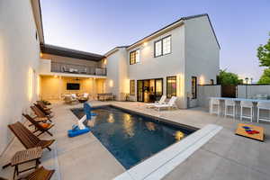 Pool at dusk with ceiling fan, an outdoor hangout area, an outdoor bar, and a patio area