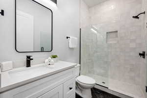 Bathroom featuring tile patterned flooring, toilet, vanity, and walk in shower