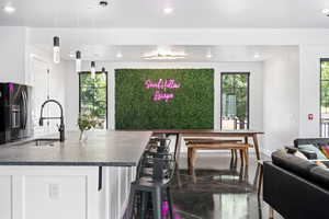 Kitchen with black fridge, plenty of natural light, sink, and pendant lighting