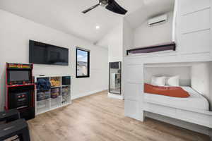 Bedroom with an AC wall unit, light hardwood / wood-style flooring, ceiling fan, and vaulted ceiling