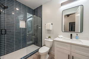 Bathroom featuring wood-type flooring, toilet, walk in shower, and vanity