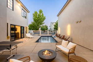 Pool at dusk with a patio area and an outdoor living space with a fire pit