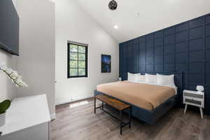 Bedroom with high vaulted ceiling and hardwood / wood-style floors