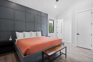 Bedroom with high vaulted ceiling and light wood-type flooring